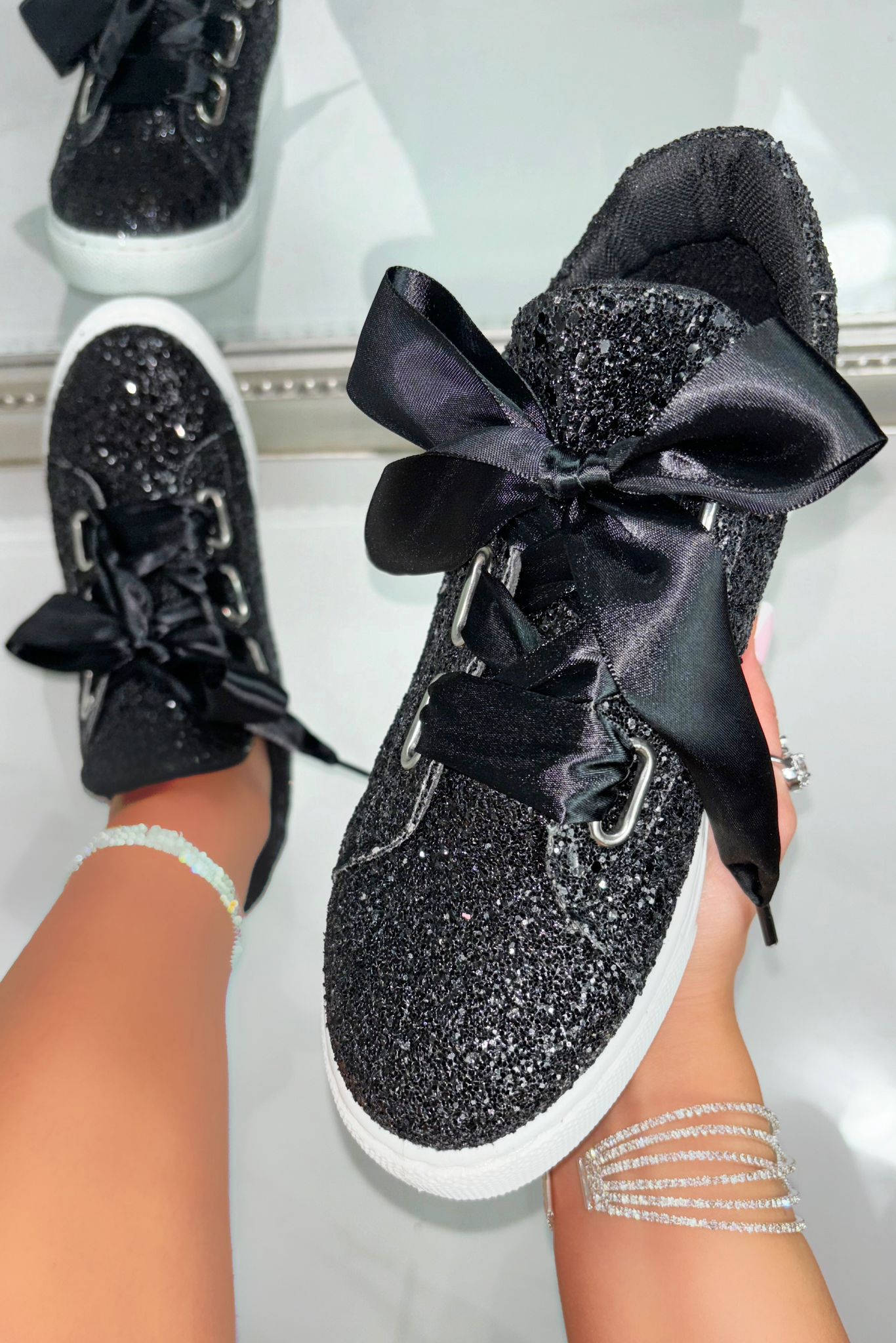 Black glittery sneakers with large bows on a light background