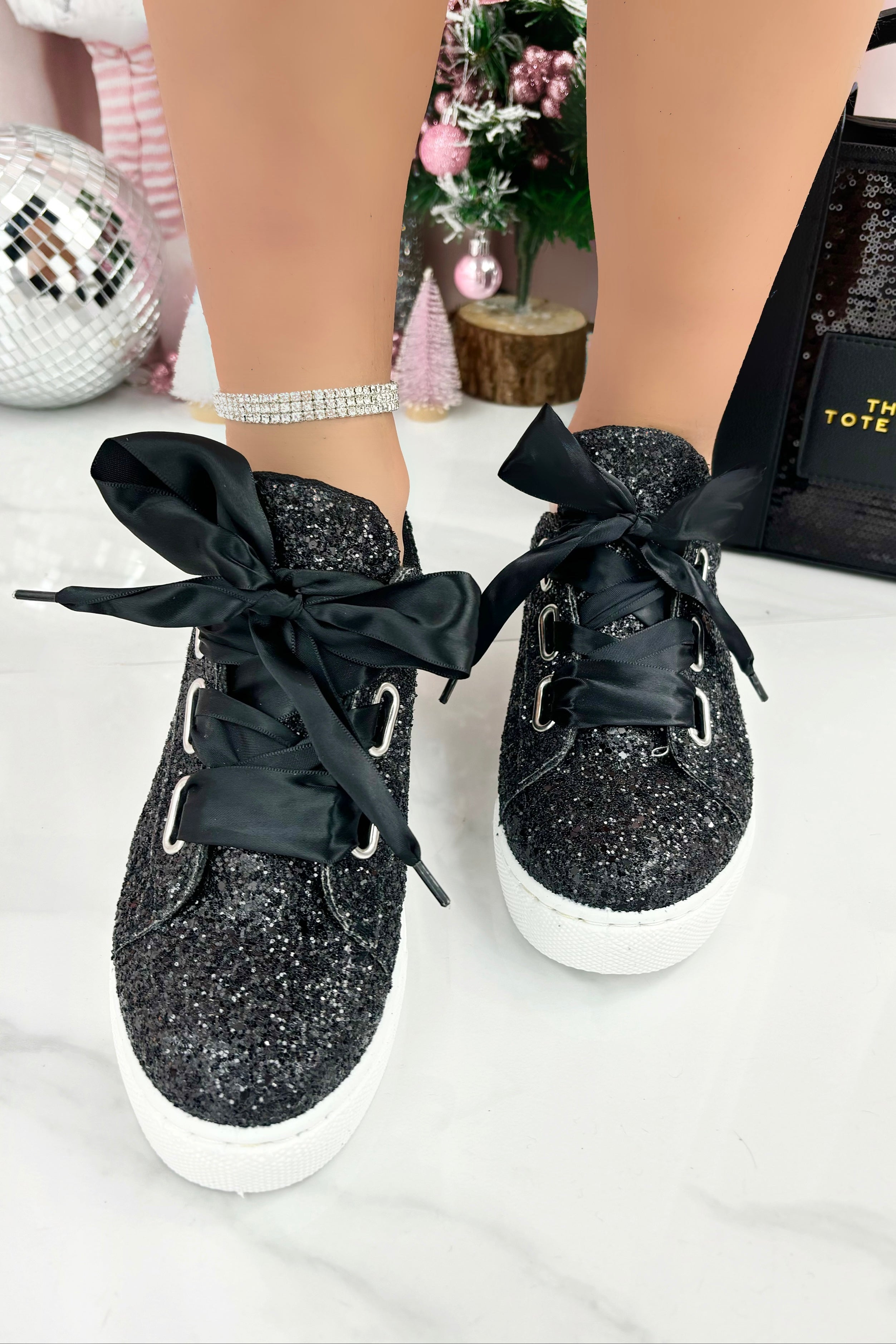 Black glittery sneakers with black ribbons on a white surface.