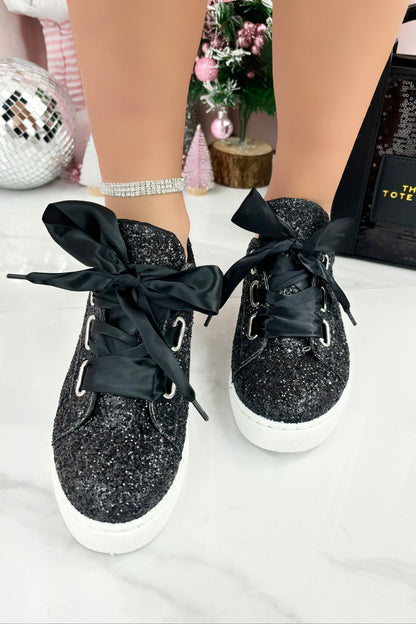 Black glittery sneakers with black ribbons on a white surface.