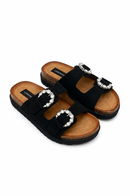 A pair of black double-strap slide sandals with silver-tone buckle embellishments set with clear rhinestones, shown on a plain white background.