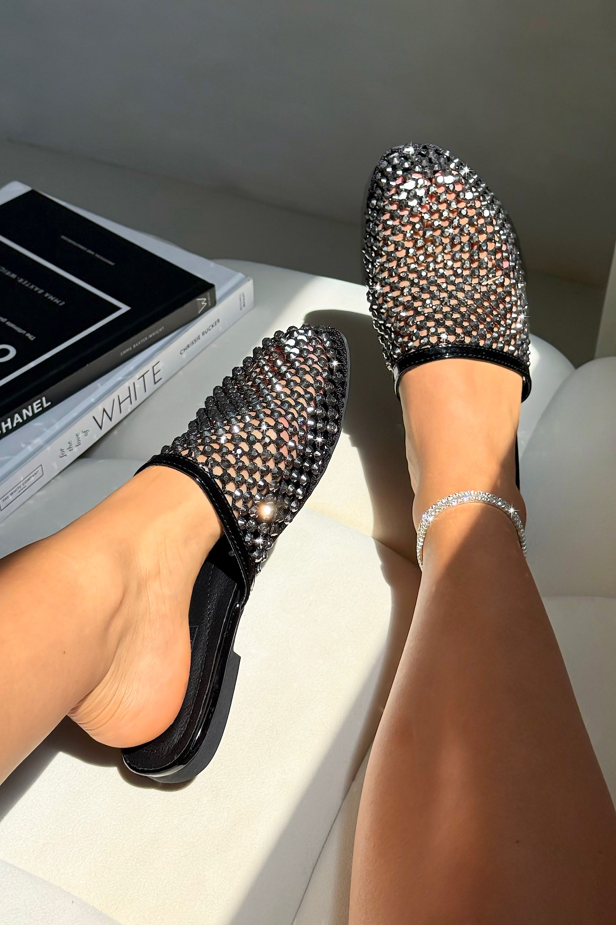 Black stud-style flats worn by a person with a blurred background