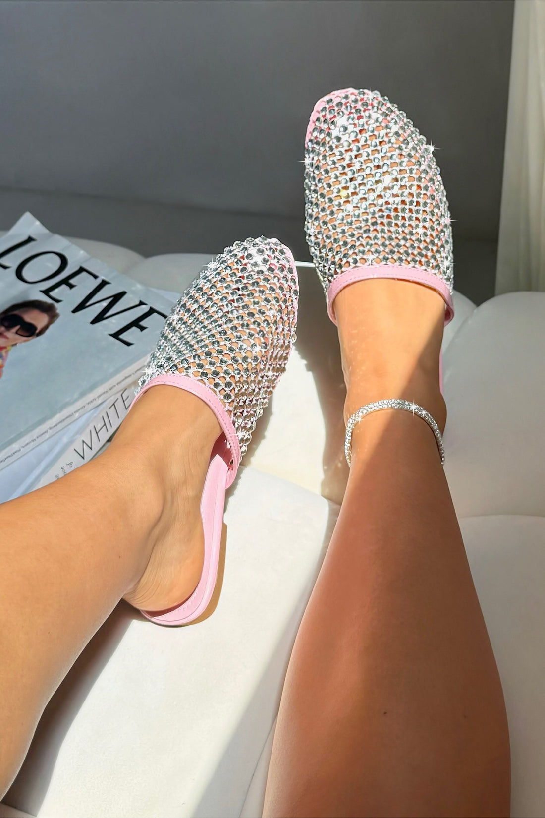 Shiny rhinestone flats on feet with a magazine in the background