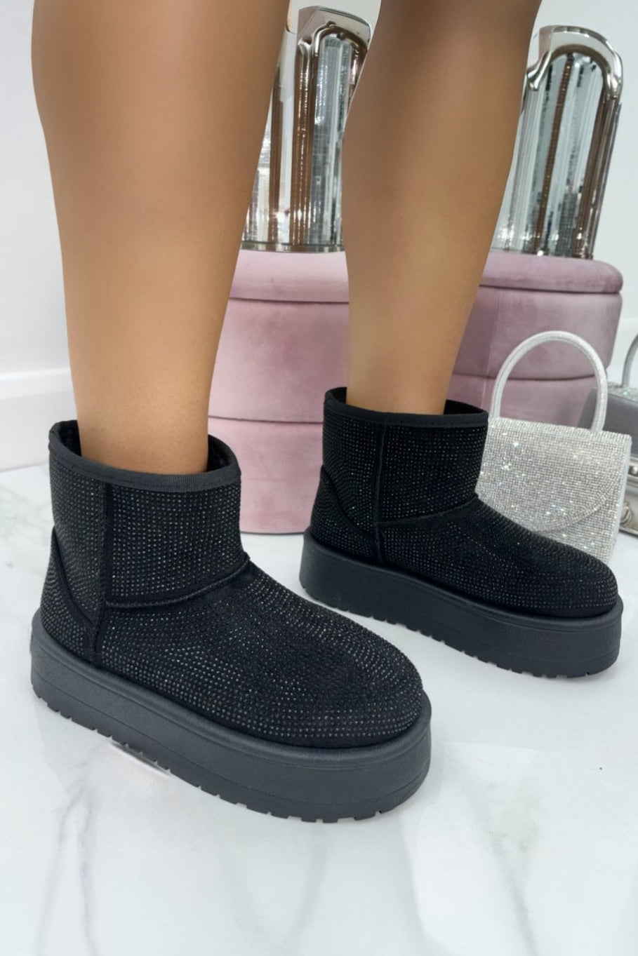 Black winter boots worn indoors with a blurred background