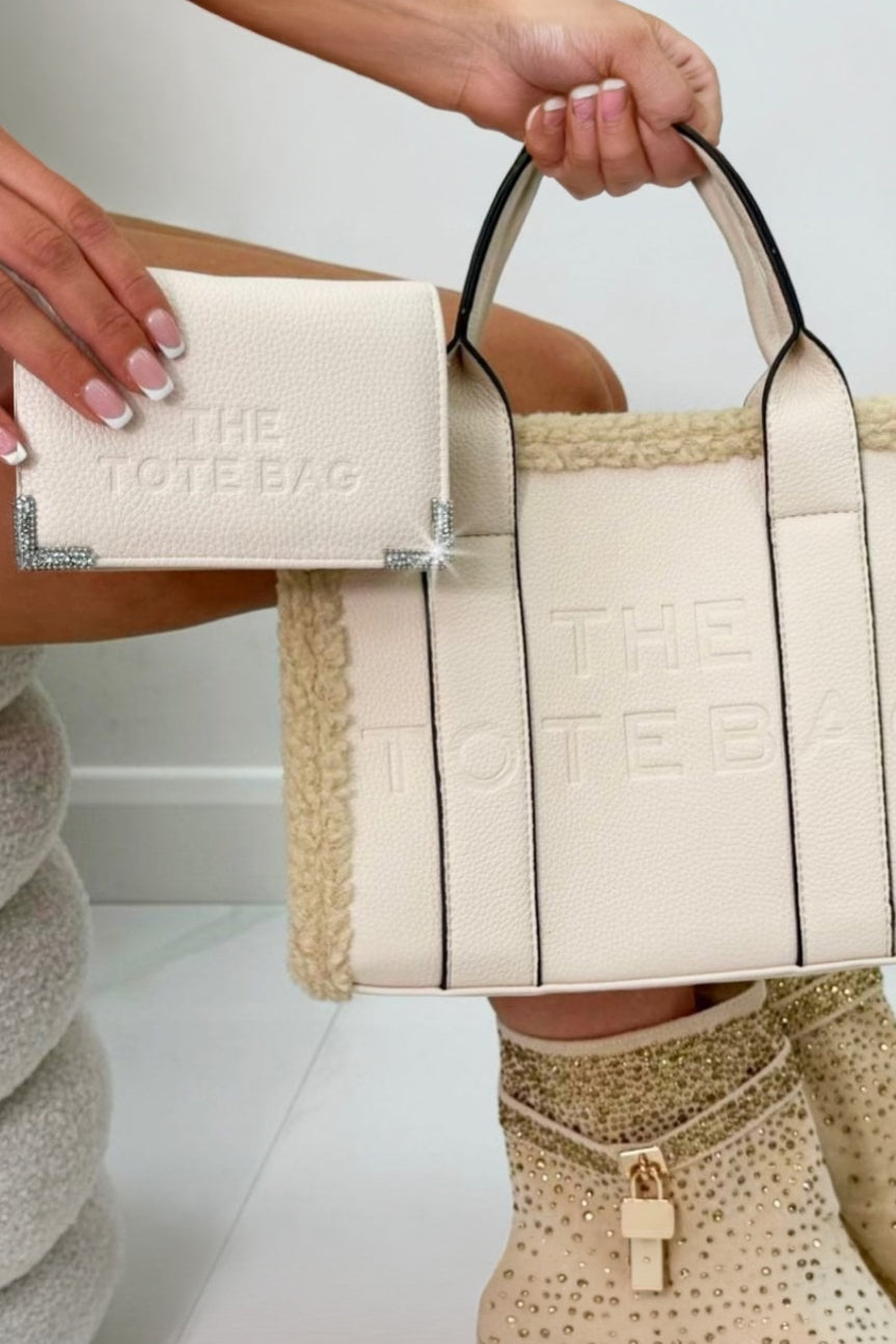 Person holding a beige tote bag with &