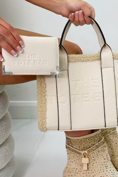 Person holding a beige tote bag with &