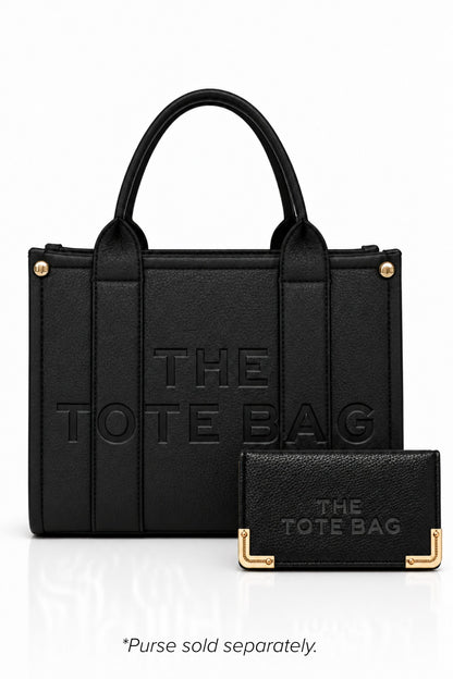 Black faux leather tote bag with two rounded top handles, embossed "THE TOTE BAG" lettering on the front, contrast stitching. gold tone hardware and a detachable adjustable black shoulder strap. With a TOTE purse pictured in front of bag.