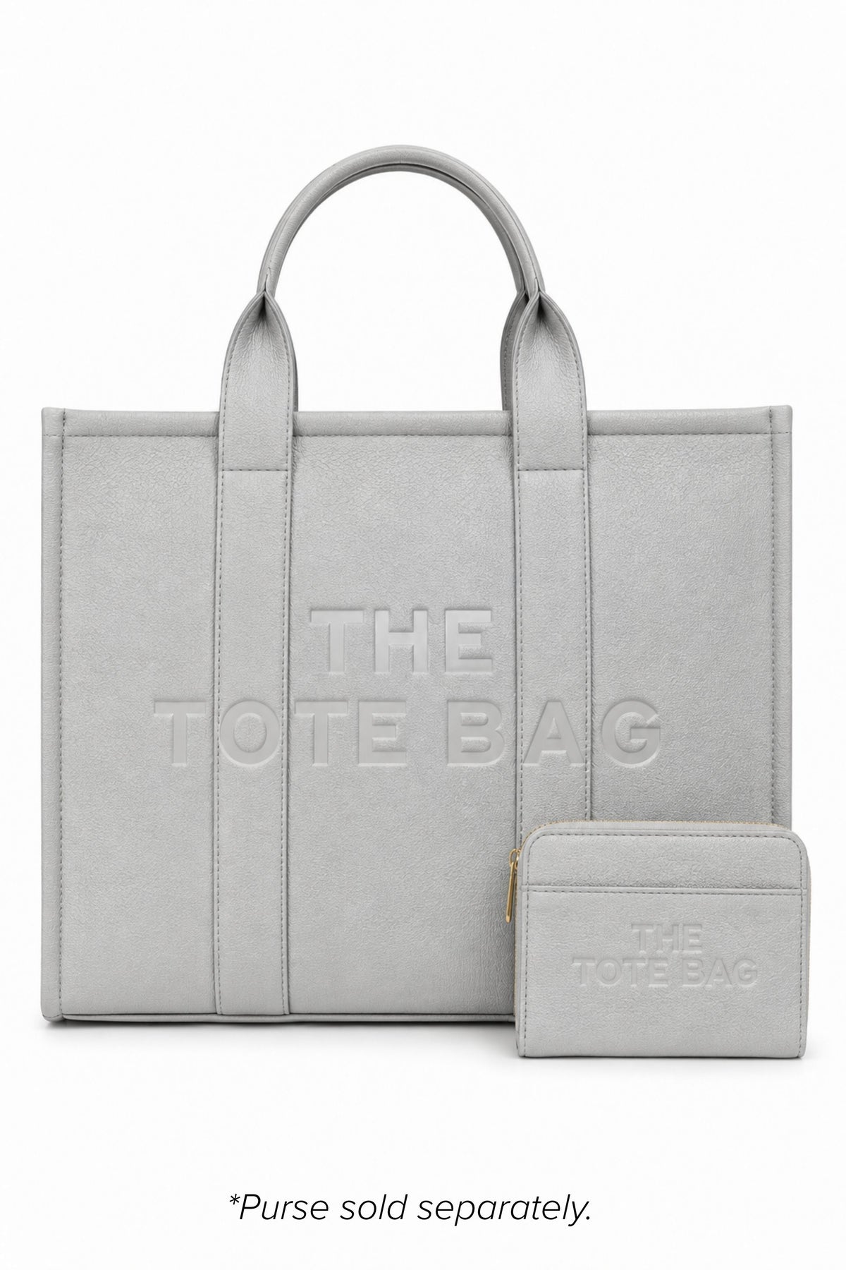 Grey faux leather structured tote bag with two rounded top handles, embossed. "THE TOTE BAG" lettering on the front, vertical stitched panels, contrast edging and gold- tone stud details. With grey-tone tote purse pictured in front of bag. 