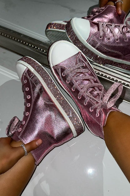 Pink glittery high-top sneakers being worn with a reflective surface in the background
