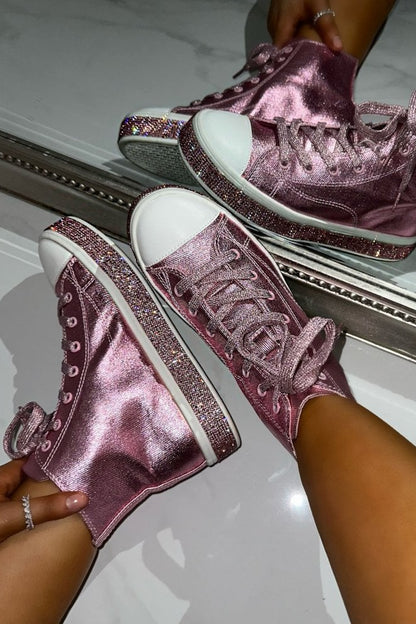 Pink glittery high-top sneakers being worn against a mirror.